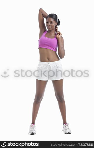 Portrait of young woman stretching arms over white background
