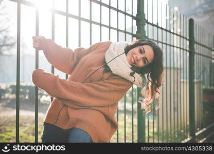 Portrait of young woman swinging from park railings