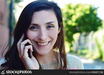 Portrait of young woman talking on her mobile phone. Outdoors.