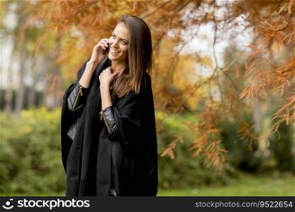 Portrait of young woman using mobile phone in autumn park