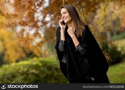 Portrait of young woman using mobile phone in autumn park