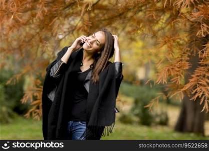 Portrait of young woman using mobile phone in autumn park