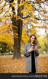 Portrait of young woman using mobile phone in autumn park