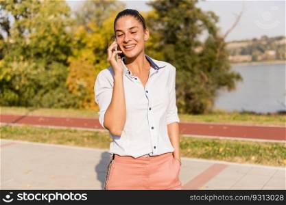 Portrait of young woman using mobile phone in the park by river
