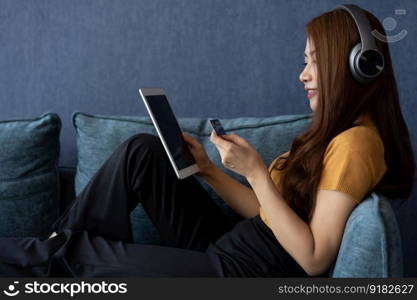 Portrait of young woman wear headphones and holding tablet and banking credit card, transferring money online, shopping goods in internet store, purchasing services, satisfied with secure payments.