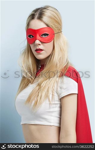 Portrait of young woman wearing superhero costume against blue background