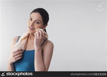Portrait of young woman wiping her cheek with napkin isolated over gray background