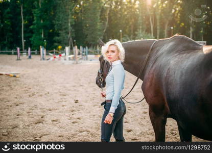 Portrait of young woman with brown horse. Equestrian sport, attractive lady and beautiful stallion. Portrait of young woman with brown horse