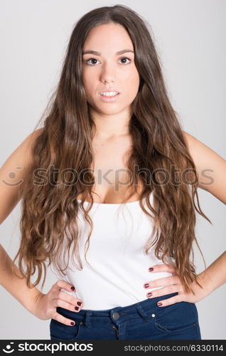 Portrait of young woman with long hair wearing white t-shirt and blue jeans on white background