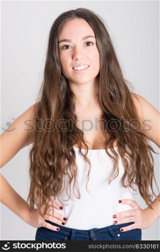 Portrait of young woman with long hair wearing white t-shirt and blue jeans on white background
