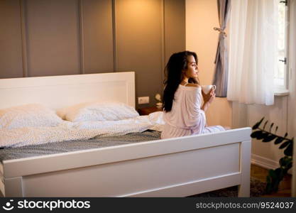 Portrait of young woman with mug in bedroom