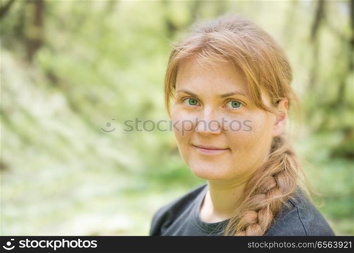 Portrait of young woman with red hair. Portrait of young woman with red hair and plait in the green forest