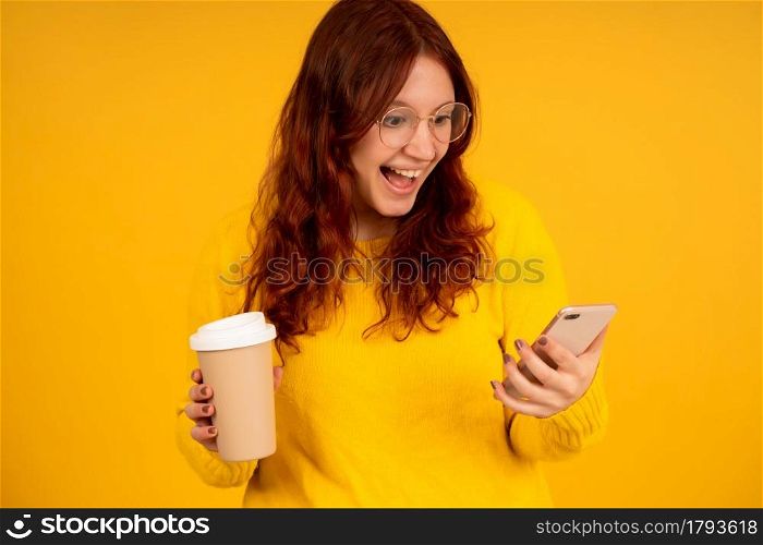 Portrait of young woman with shocked expression on her face while using a mobile phone against isolated background.