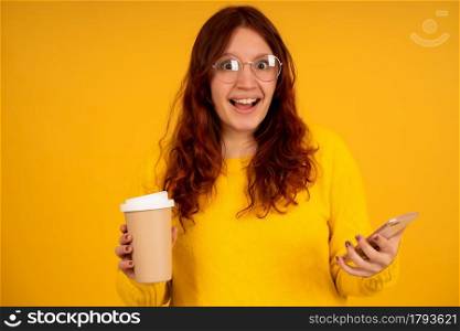 Portrait of young woman with shocked expression on her face while using a mobile phone against isolated background.