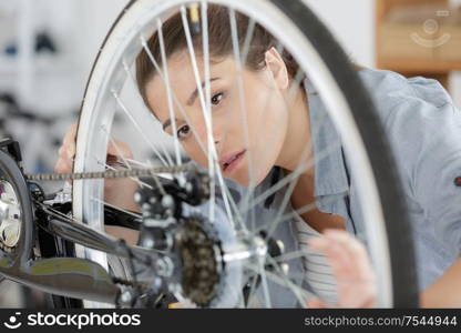 portrait of young woman working on a bike wheel