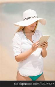 Portrait of young woman working on digital tablet at beach at windy day