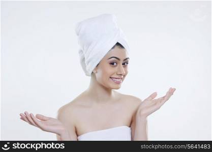 Portrait of young woman wrapped in towel gesturing against white background