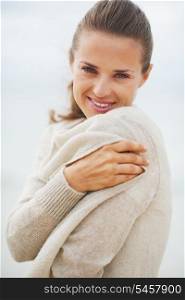Portrait of young woman wrapping in sweater on coldly beach