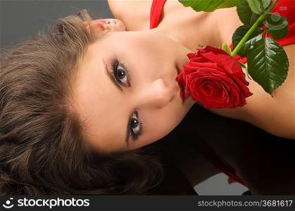 portrait on black of a pretty brunette with a red rose