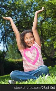 Portrait photograph of a beautiful young smiling happy mixed race interracial African American girl, shot outside in a park with her arms in the air
