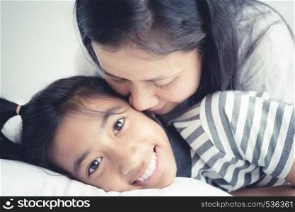 Portrait picture of love family mother on the kiss daughter; Cute girl smile beautiful and happy on bed.