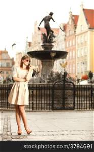 Portrait pretty woman outdoors on the street of the old town european city Gdansk Danzig Neptune fountain