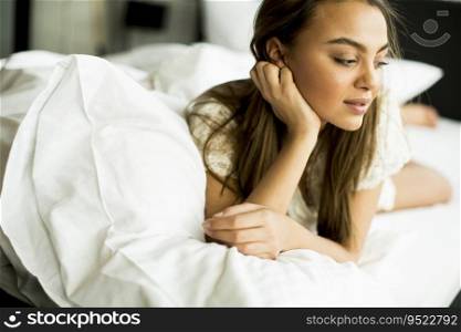 Portrait pretty young girl on bed in modern apartment in the morning