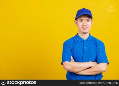 Portrait professional attractive delivery happy man standing he smile wearing blue t-shirt and cap uniform crossed arms looking to camera, studio shot isolated on yellow background