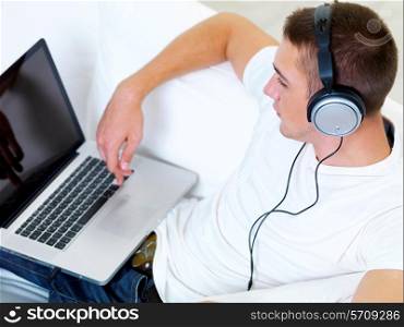 portrait profile young guy listening music in headphone from laptop at home