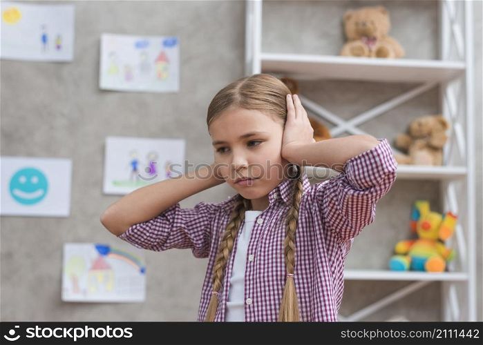 portrait sad girl covering her ears with two hands