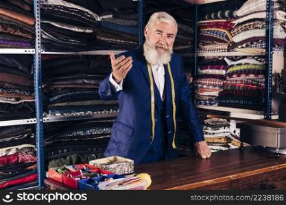portrait senior male fashion designer inviting someone his shop