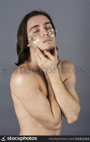 portrait shirtless man with flowers his face