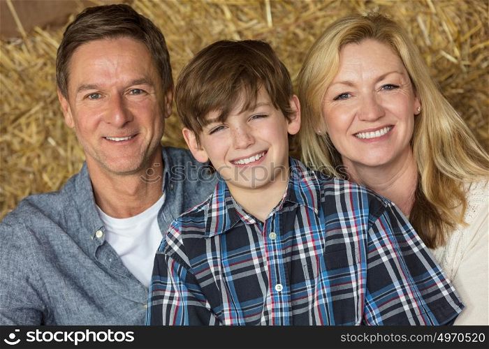 Portrait shot of an attractive, successful and happy family, middle aged man and woman couple with young boy child son sitting smiling together on hay or straw bales