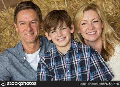 Portrait shot of an attractive, successful and happy family, middle aged man and woman couple with young boy child son sitting smiling together on hay or straw bales