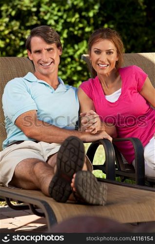 Portrait shot of an attractive, successful and happy middle aged man and woman couple in their thirties, sitting togther holding hands and smiling.