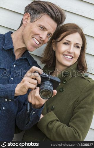 Portrait shot of an attractive, successful and happy middle aged man and woman couple together outside taking photographs with a digital camera