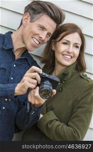 Portrait shot of an attractive, successful and happy middle aged man and woman couple together outside taking photographs with a digital camera