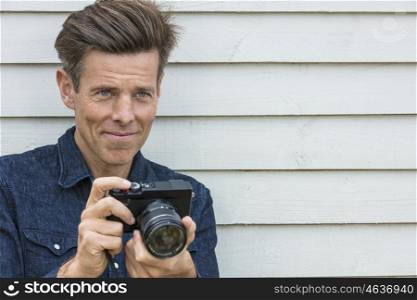 Portrait shot of an attractive, successful and happy middle aged man male photographer outside taking photographs with a digital camera