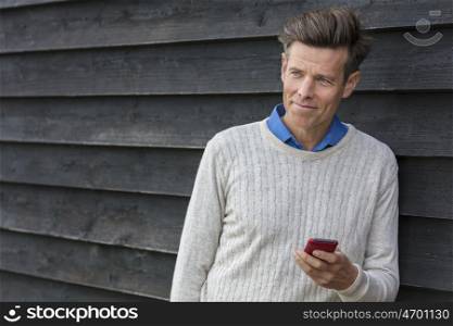 Portrait shot of an attractive, successful and happy middle aged man male outside using a mobile cell phone