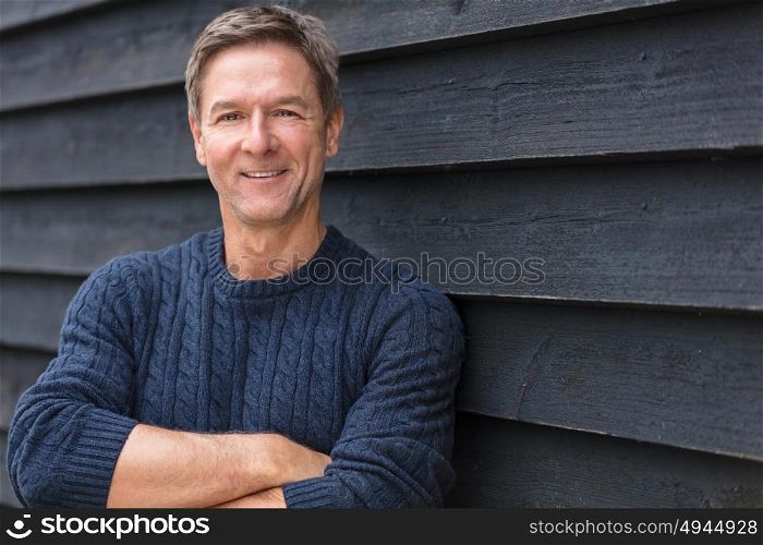 Portrait shot of an attractive, successful and happy middle aged man male arms folded outside wearing a blue sweater