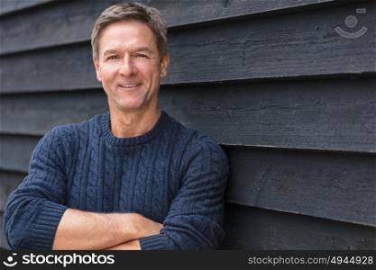 Portrait shot of an attractive, successful and happy middle aged man male arms folded outside wearing a blue sweater
