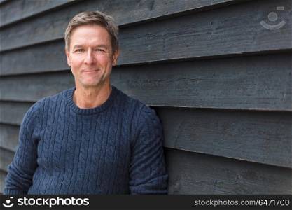 Portrait shot of an attractive, successful and happy middle aged man male smiling outside wearing a blue sweater. Happy Middle Aged Man Outside