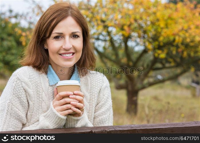 Portrait shot of an attractive, successful and happy middle aged woman female outside drinking coffee in a disposable takeaway cup.. Happy Attractive Middle Aged Woman Drinking Coffee
