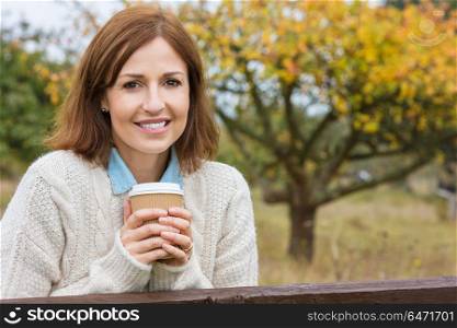 Portrait shot of an attractive, successful and happy middle aged woman female outside drinking coffee in a disposable takeaway cup.. Happy Attractive Middle Aged Woman Drinking Coffee