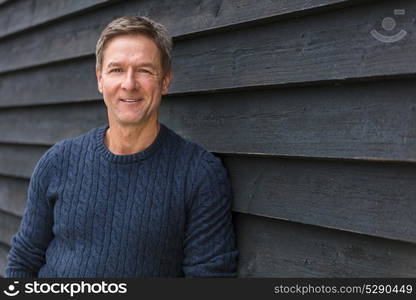 Portrait shot of an attractive, successful and happy smiling middle aged man male outside wearing a blue sweater