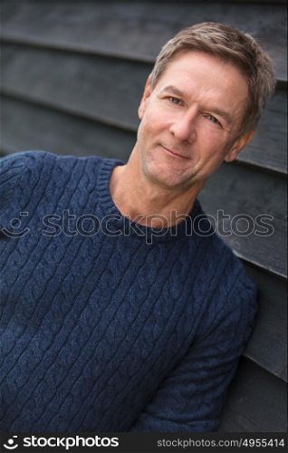 Portrait shot of an attractive, successful handsome and happy middle aged man male outside wearing a blue sweater