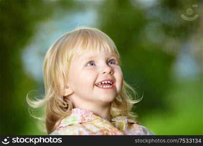 Portrait - small amusing blonde girl laughs in park