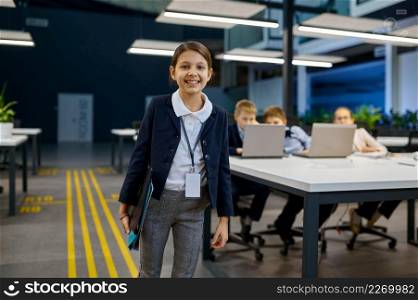 Portrait smart little smiling businesswoman looking at camera with children coworker on background. Portrait of smart little smiling business girl