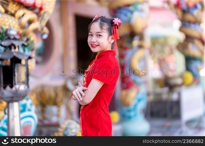Portrait smiles Cute little Asian girl wearing red cheongsam dress traditional decoration for Chinese new year festival celebrate culture of china at Chinese shrine