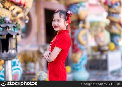 Portrait smiles Cute little Asian girl wearing red cheongsam dress traditional decoration for Chinese new year festival celebrate culture of china at Chinese shrine